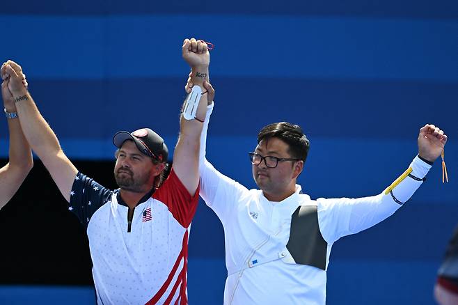 4일 파리올림픽 남자 양궁 개인전에서 브레이디 엘리슨(왼쪽)이 금메달을 딴 김우진 선수의 손을 들어 축하를 하고 있다. /AFP 연합뉴스