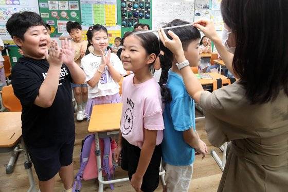 지난해 2학기 개학을 맞은 8월 대구 중구 한 초등학교에서 담임 선생님이 방학을 보내고 돌아온 학생들의 키를 재고 있다.뉴스1