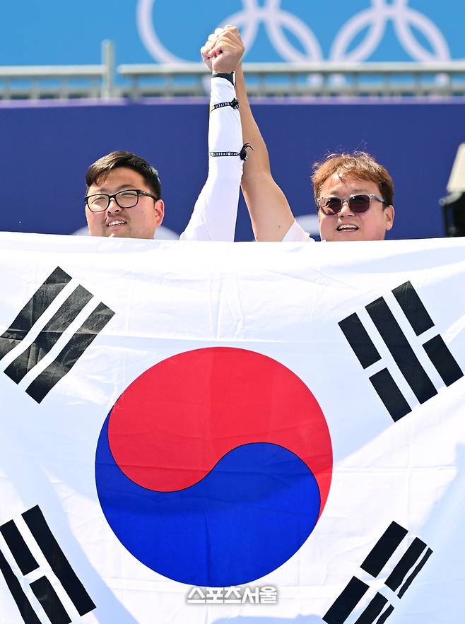 양궁 국가대표 김우진(왼쪽)이 4일(한국 시간) 프랑스 파리 앵발리드에서 열린 파리올림픽 양궁 남자 개인전 미국의 브래디 엘리슨과의 결승전에서 승리하며 3관왕을 달성한 뒤 박성수 감독과 함께 태극기를 들고 기뻐하고 있다. 김우진은 한국 선수 올림픽 역다 최다인 5개의 금메달을 획득했다. 2024. 8. 4. 파리 | 박진업 기자 upandup@sportsseoul.com