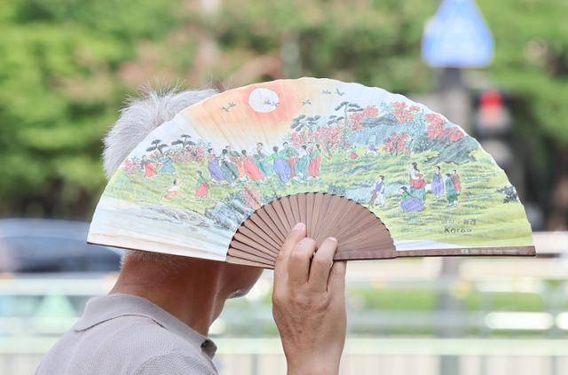 무더위가 이어진 18일 서울 종로구 광화문광장에서 한 시민이 부채로 햇빛을 가리며 이동하고 있다. 뉴스1