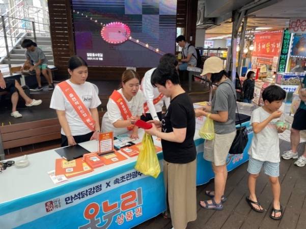 7월 강원도 속초관광수산시장에서 진행한 카드형 온누리상품권 스타가맹점 행사에서 고객들이 홍보부스에서 카드형 온누리 상품권 쿠폰을 받아가고 있다. 사진 제공=소진공