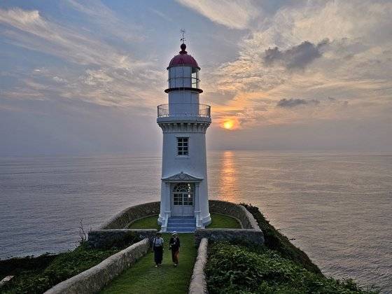 한국에서 가장 아름다운 등대로 꼽히는 어청도 등대. 단아한 등대 뒤편 망망대해에서 노을이 진다 .