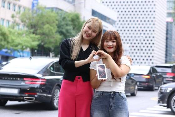 아이폰16 출시일인 20일 오전, 방송인 엄지윤씨(왼쪽)가 LG유플러스의 사전예약 고객인 김민선씨에게 '아침배송' 이벤트를 통해 아이폰16 프로를 직접 전달했다. 사진 LG유플러스
