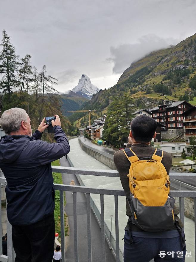 체르마트 시내를 흐르는 빙하천 다리 위에서 마테호른 봉우리를 바라보는 관광객들.