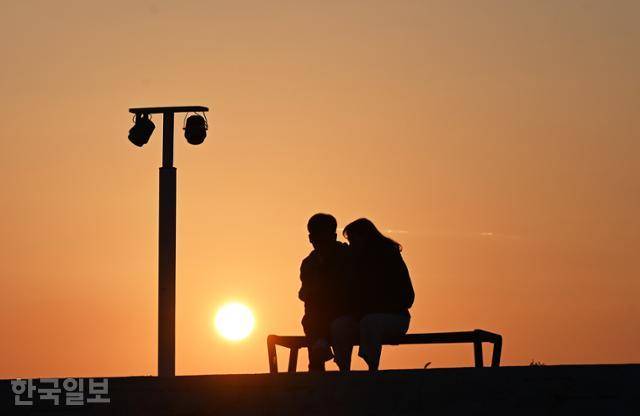여행객이 오이도 빨강등대 제방에서 석양에 젖어 있다.