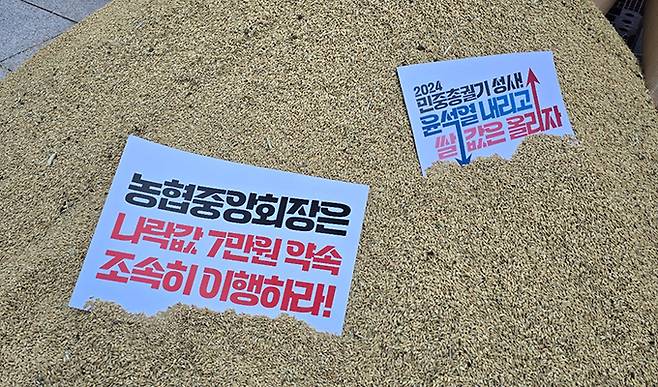 전국농민회총연맹(이하 ‘전농’)과 전국쌀생산자협회가 24일 오후 서울 농협중앙회 본관 앞에서 기자회견을 열고 나락값 7만원 공약 이행 등 즉각적인 쌀값 안정화 대책 마련을 촉구하는 가운데 나락포대에 항의 피켓이 놓여있다.