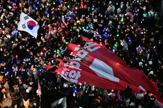 윤석열 대통령에 대한 탄핵소추안이 주말 새 열린 국회 본회의에서 의결 정족수 미달로 불성립된 후 첫 평일인 9일 서울 여의도 일대에 모인 시민들이 탄핵안 투표를 거부한 국민의힘을 규탄하러 중앙당사로 행진한 후 현수막을 찢는 퍼포먼스를 하고 있다. 이한호 기자