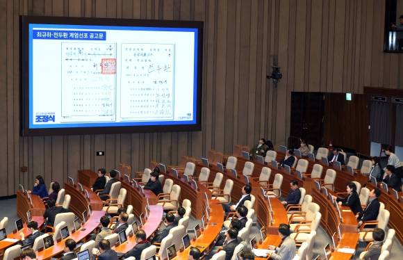 국회에 뜬 ‘전두환 계엄 공고문’ - 13일 국회에서 열린 ‘윤석열 대통령 위헌적 비상계엄 선포 내란행위 관련 긴급 현안질문’에서 조정식 더불어민주당 의원이 띄운 ‘최규하·전두환 계엄선포 공고문’이 화면에 나오고 있다. 뉴시스