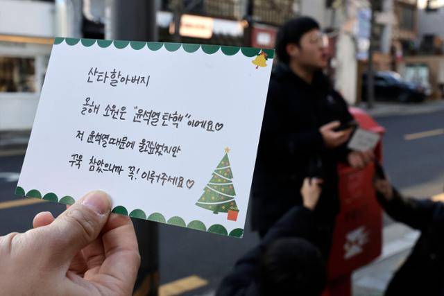 윤석열퇴진전국대학생시국회의가 23일 서울 용산구 한남동 우체국 앞에서 대학생이 윤석열 대통령에게 보내는 크리스마스카드를 우체국 등기로 발송 전 보여주고 있다. 뉴시스