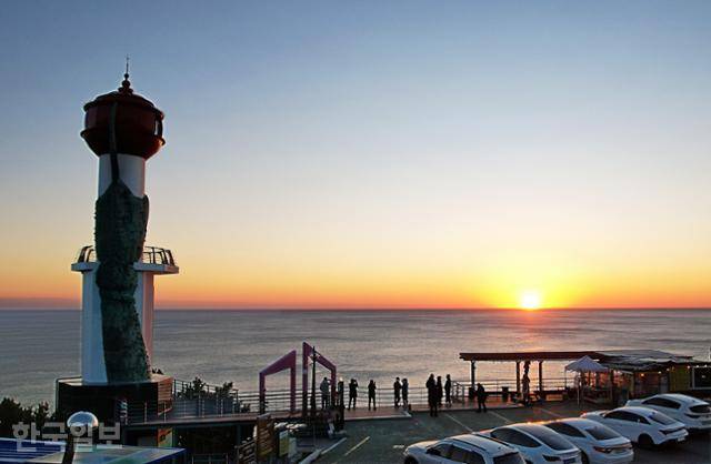 영덕 일출 명소인 창포말등대 너머 수평선에서 말갛게 해가 떠오르고 있다.