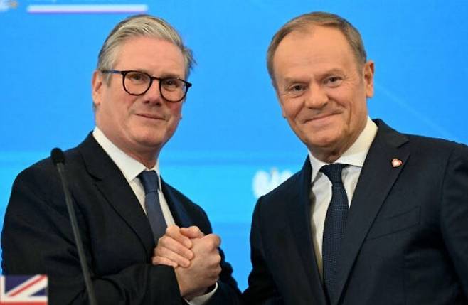 키어 스타머 영국 총리(왼쪽)와 도날트 투스크 폴란드 총리가 17일(현지시간) 폴란드 바르샤바에서 정상회담 후 공동 기자회견을 마친 다음 손을 맞잡고 있다. AFP연합뉴스