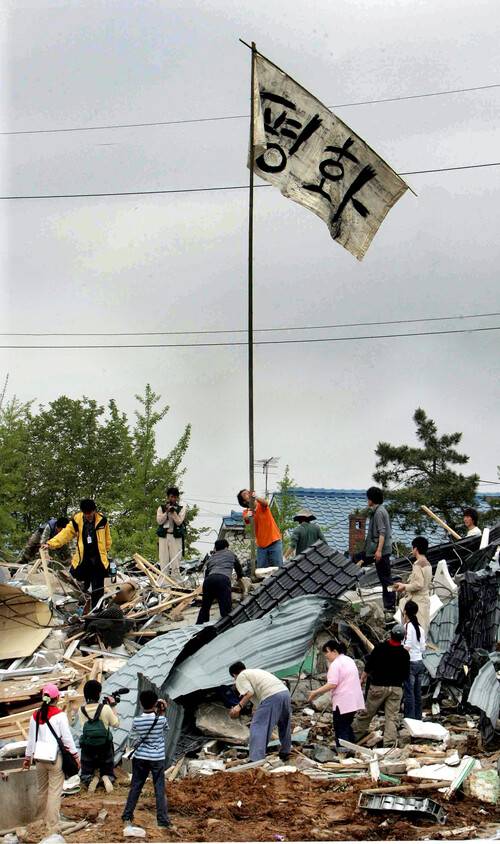 2006년 5월5일 오전 미군기지 확장 예정지인 경기 평택시 팽성읍 대추리 대추분교에서 마을 주민들과 ‘평택 미군기지 확장저지 범국민 대책위원회’ 회원들이 전날 국방부와 경찰이 장악해 허물어 버린 학교 건물 잔해 위에 ‘평화’라고 쓰인 깃발을 세우고 있다. 김태형 기자 xogud555@hani.co.kr