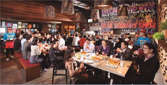 제너시스BBQ의 'bbq 프리미엄 카페'에서 고객들이 치킨, 파스타, 피자, 스테이크, 샐러드 등을 먹으며 담소를 나누고 있다.