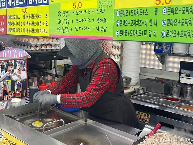 7일 낮 12시쯤 서울 동작구 노량진 컵밥 거리에서 한 상인이 털모자와 마스크를 착용하고 요리를 하고 있다. /사진=이현수 기자.