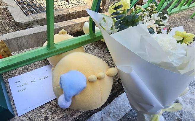 지난 10일 교사가 학교에서 8살 학생에서 흉기를 휘둘러 숨지게 한 사건이 발생한 대전의 한 초등학교 정문 앞에 숨진 어린이를 추모하는 글이 적힌 엽서와 국화 꽃다발, 인형 등이 놓여있다. 엽서에는 “아가, 아프지 말고 편히 눈 감으렴. 미안해”라고 적혀 있다. 최예린 기자