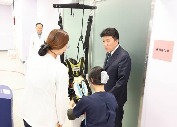 지난 17일 함영주(맨 오른쪽) 하나금융지주 회장이 서울 마포구 푸르메재단 넥슨어린이재활병원에서 열린 ‘장애 아동·청소년을 위한 재활 및 학습 보조기구 전달식’에 참석해 중추신경계 발달치료를 받는 장애 아동에게 격려의 말을 전하고 있다. 하나금융지주 제공
