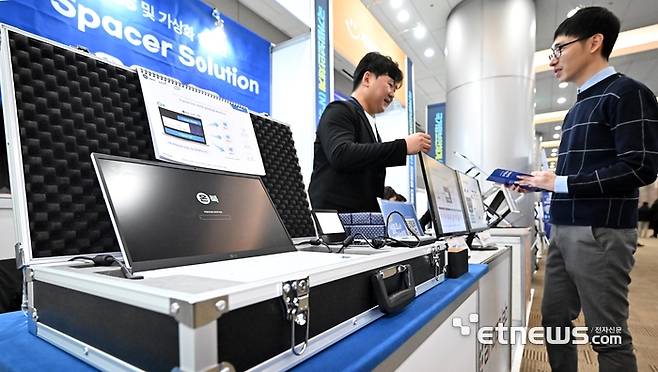 국가망보안체계(N²SF) 전망과 대응 콘퍼런스가 28일 서울 강남구 코엑스에서 열렸다. 참석자가 아홉랩의 온북 OS 및 가상화 솔루션 V-스페이서 솔루션을 살펴보고 있다. 이동근기자 foto@etnews.com