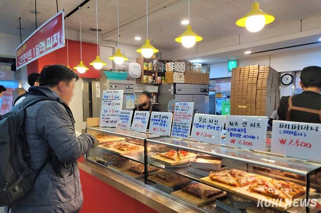 한 직장인이 13일 서울 여의도역에서 조각 피자를 주문하고 있다. 김건주 기자