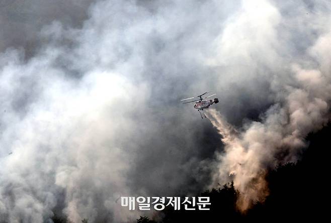 경남 산청군에서 발생한 산불 사흘째 23일 단성면 일대에 산불이 마을 쪽으로 향하자 헬기가 물을 뿌리며 산불을 진압하고 있다. 이충우 기자
