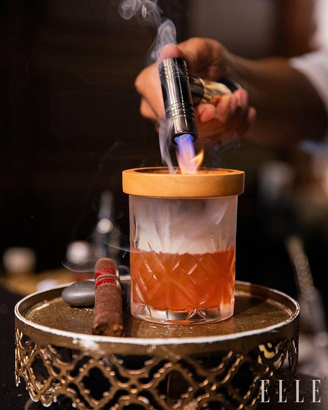 꼬냑 레미 마틴 VSOP와 치앙마이에서 바삭하게 구운 돼지 지방을 씻은 캄파리, 시가 연기와 야생 꿀을 사용한 칵테일 ‘Jack Bain’s Will’.