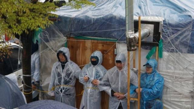 ▲ 아사히글라스비정규직 노동자들이 회사 앞에 설치한 천막을 지키기 위해 천막을 붙들기 위해 묶어둔 밧줄을 목에 걸고 있다. ⓒ아사히글라스비정규직지회