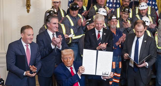도널드 트럼프 미국 대통령이 8일(현지시간) 백악관 이스트룸에서 광부들이 지켜보는 가운데 미국 석탄 생산을 촉진을 위한 행정명령에 서명한 뒤 이를 들어보이고 있다. 워싱턴=EPA연합뉴스