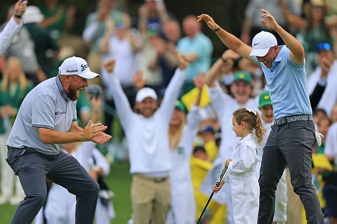 로리 매킬로이(오른쪽)와 셰인 라우리(왼쪽)가 10일 마스터스 파3 콘테스트 마지막홀에서 매킬로이이 딸 포피(가운데)의 긴 퍼트가 홀에 들어가자 환호하고 있다. 오거스타|EPA 연합뉴스