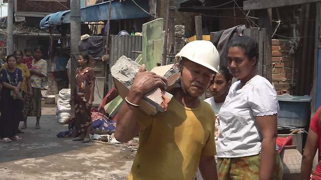무너진 건물에서 손수 벽돌을 옮기는 민민툰 씨