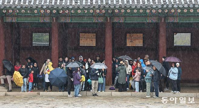 14일 오전 서울 종로구 경복궁에서 갑작스러운 비바람에 외국인 관광객들이 담 지붕 아래서 비를 피하고 있다. 송은석 기자 silverstone@donga.com