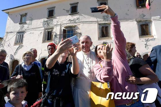 프란치스코 교황이 4일(현지시간) 지진 피해 지역인 이탈리아 중부 아쿠몰리를 방문해 주민들과 셀카를 찍고 있다.ⓒ AFP=뉴스1 ⓒ News1 우동명 기자