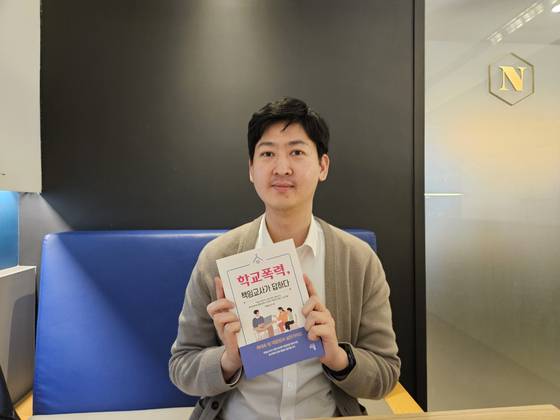 성남에서 국어교사로 재직중인 김성우(40)씨가 지난 3월 출간된 '학교폭력,책임교사가 답하다' 책을 들고 포즈를 취하고 있다. 김씨는 ″학생들의 행복이 최우선이어야 하는데, 학폭 처리 과정에서 상처 입는 경우를 많이 봐 안타깝다″고 말했다. 신혜연 기자.