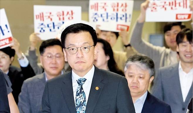 < 최상목 美 출국…관세협상 중단하라는 시위대 > 최상목 부총리 겸 기획재정부 장관이 미국 워싱턴DC에서 열리는 ‘한·미 2+2 통상 협의’를 위해 22일 인천국제공항 출국장으로 이동하고 있다. 공항에선 진보당 의원들이 ‘매국 협상을 중단하라’며 피켓 시위를 벌였다. 뉴스1