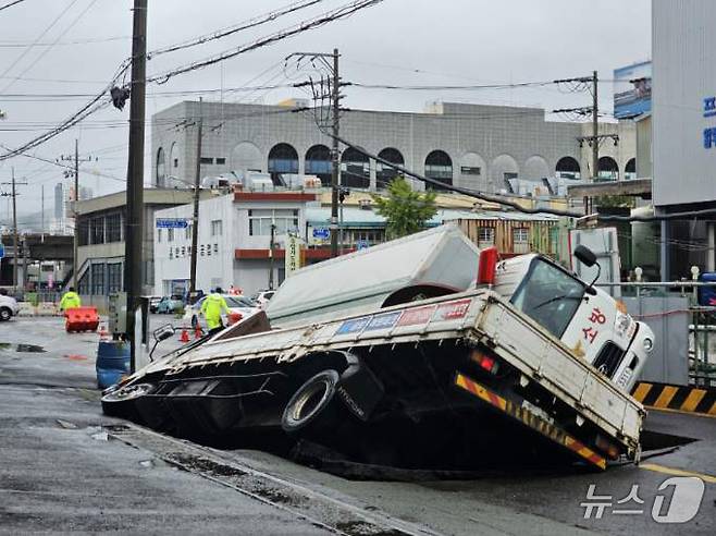 21일 오전 8시45분께 부산 사상구 한 도로에서 가로 10m, 세로 5m, 깊이 8m 가량의 대형 땅꺼짐 현상(싱크홀)이 발생해 도로에서 배수 지원을 하던 삼락119안전센터 배수 차량과 5톤 트럭이 빠져있다. (부산소방재난본부 제공) 2024.9.21/뉴스1 ⓒ News1 윤일지 기자