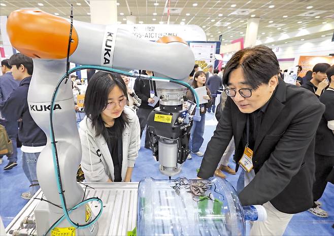 25일 ‘2025 월드IT쇼’를 찾은 관람객들이 이화여대 부스에서 글로벌 기업 쿠카의 협동로봇을 살펴보고 있다. /이솔 기자