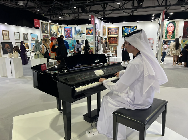 한 아랍인 연주자가 전시회장 안에서 피아노를 치며 분위기를 돋구고 있다