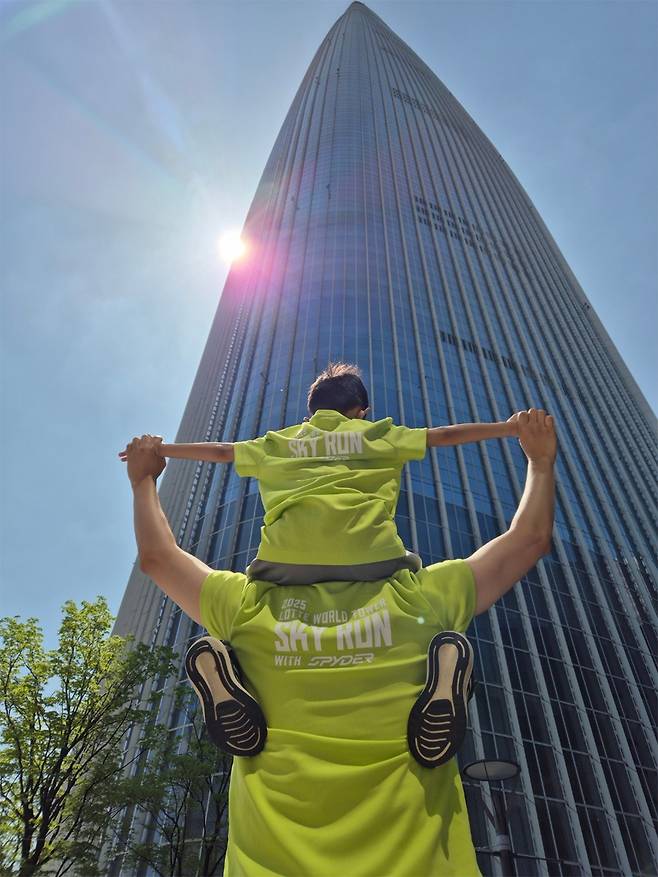 지난 20일 서울 송파구 롯데월드타워에서 열린 ‘2025 롯데월드타워 스카이런(SKY RUN)’에 아들과 함께 참가한 강태우(41)씨가 아들과 함께 롯데월드타워를 배경으로 포즈를 취하고 있다. 김동환 기자