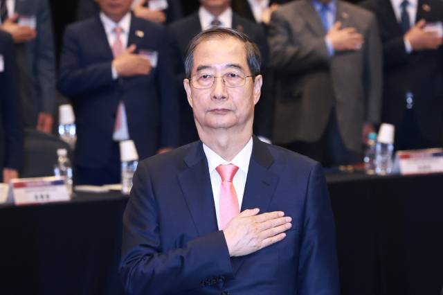 한덕수 대통령 권한대행 국무총리가 30일 서울 여의도 중소기업중앙회에서 열린 '중소기업 규제혁신 현장 소통 간담회'에서 국기에 경례하고 있다. 연합뉴스