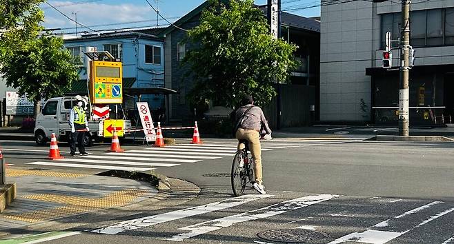 지난 29일 일본 사이타마현 야시오시 싱크홀 사고 현장을 공사 관계자가 통제하는 가운데 주민이 횡단보도를 건너고 있다. 사이타마/홍석재 특파원