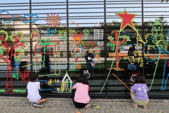 용인 백남준아트센터의 거울 같은 외벽에 마음껏 테이프를 붙여 그림 그리는 어린이들. 사진 경기문화재단