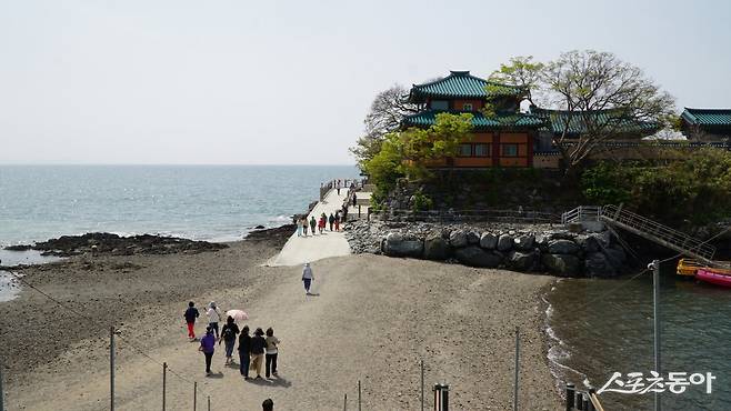 간조 때 섬과 이어진 길을 따라 간월암으로 가는 관광객들. 간월암을 찾을 때는 물때를 잘 계산해야 만조와 간조 때의 극적인 변화를 볼 수 있다 충남|김재범 기자 oldfield@donga.com
