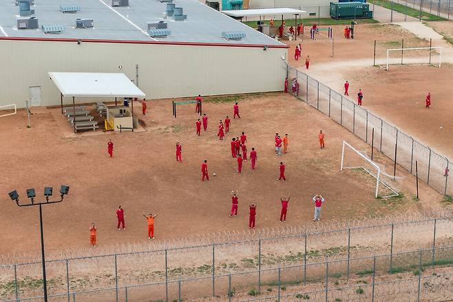28일(현지시각) 미국 텍사스 안슨의 구치소인 블루보넷 안뜰에서 드론을 향해 손을 흔드는 베네수엘라인 수감자들. 텍사스/로이터 연합뉴스