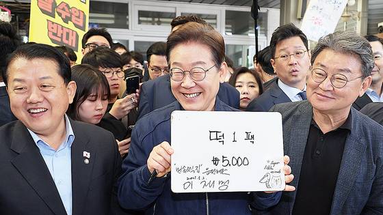 이재명 더불어민주당 대선 후보가 ‘골목골목 경청투어’ 접경지역 방문 이틀째인 2일 강원도 철원군 동송전통시장에서 한 떡집에 들러 가격판에 사인을 해준 뒤 활짝 웃고 있다. 연합뉴스