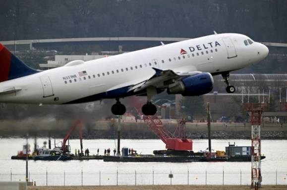 현지시간으로 2월 3일 델타항공 여객기가 워싱턴DC 인근 로널드 레이건 국제공항에서 이륙 중이다. 그 앞으로 지난 1월 29일 군용 헬리콥터인 블랙호크와 아메리칸항공 여객기 충돌로 인한 잔해를 수거하는 크레인이 보인다. 워싱턴포스트 제공