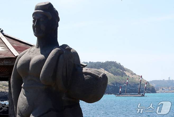 제주 해녀상 뒤로 보이는 좌초된 '페리지에어로스페이스'의 우주발사체 해상 발사장 세테시아1.