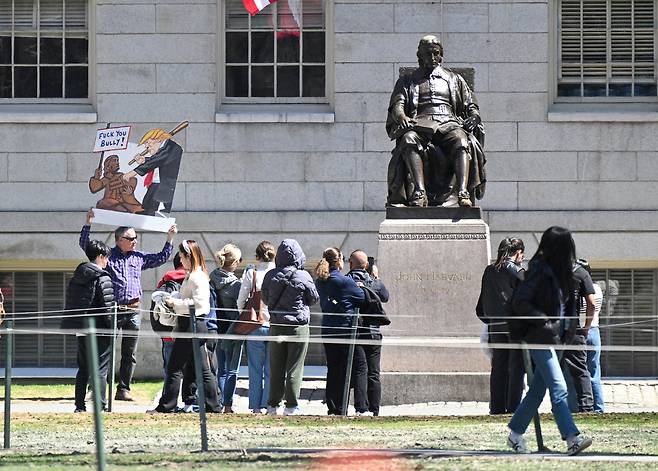지난달 17일(현지시간) 미국 매사추세츠주 케임브리지에 있는 하버드 대학교 내 존 하버드 동상 옆에서 도널드 트럼프 미국 대통령 행정부와 학생 비자 취소에 반대하는 시위가 열리고 있다. 로이터연합뉴스