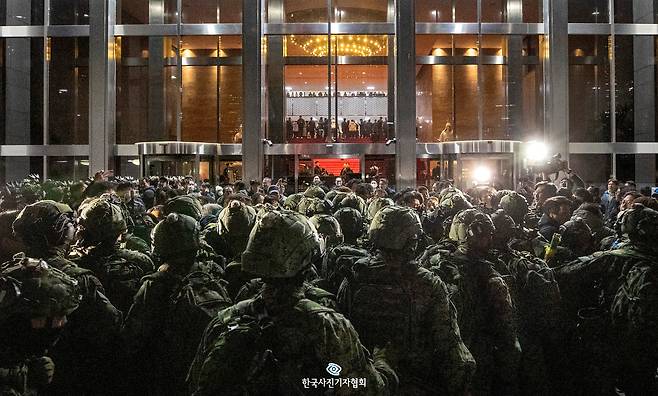 계엄군이 작년 12월 4일 새벽 국회 본관 정문 앞에서 국회 사무처 직원, 보좌진 등과 대치하고 있다. 계엄군은 정문이 막히자 사무실 유리창을 깨고 건물에 진입했지만, 의원들이 계엄 해제 요구안 표결을 위해 모인 본회의장에 들어가지는 않았다. /김지호기자