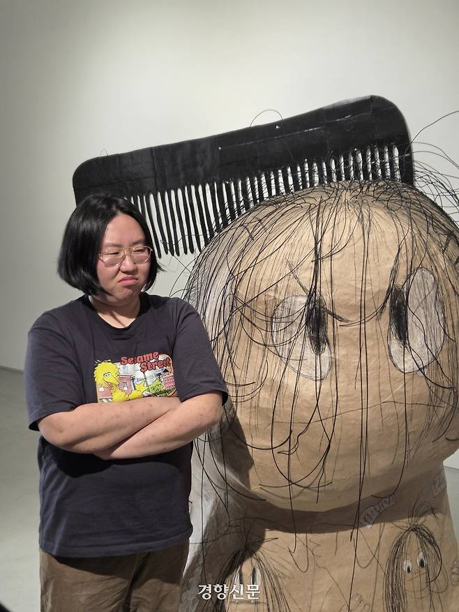 작가 신민이 서울 용산구 P21갤러리에 전시된 ‘유주얼 서스펙트-민정’ 옆에서 포즈를 취하고 있다. 윤승민 기자