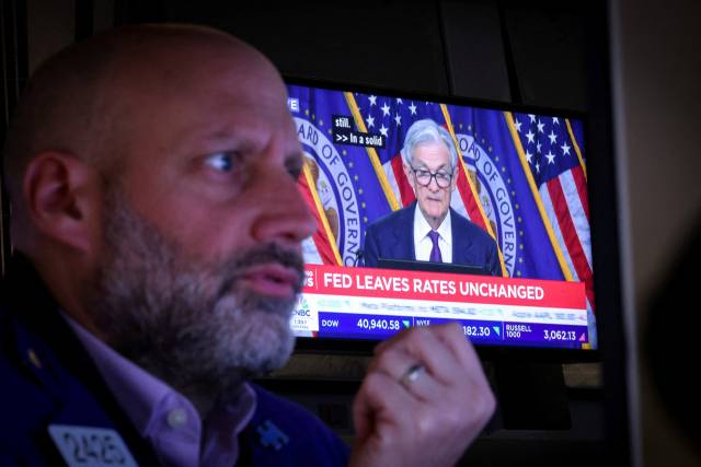 7일(현지 시간) 미국 뉴욕 뉴욕증권거래소(NYSE)에서 제롬 파월 연방준비제도(Fed·연준) 의장의 기자 회견 중계 화면 앞에서 한 트레이더가 업무를 보고 있다. 로이터연합뉴스