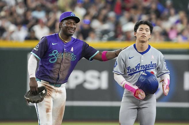 김혜성(오른쪽)이 6회 안타후, 비디오판독 결과 아웃으로 번복되자 애리조나 유격수 페르도모가 웃으며 위로하고 있다. AP·연합뉴스