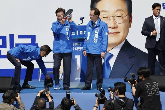 이재명 더불어민주당 대통령 후보가 12일 오전 서울 종로구 청계광장에서 열린 중앙선거대책위원회 출정식에서 구두를 벗고 운동화를 신고 있다. 2025.5.12 뉴스1